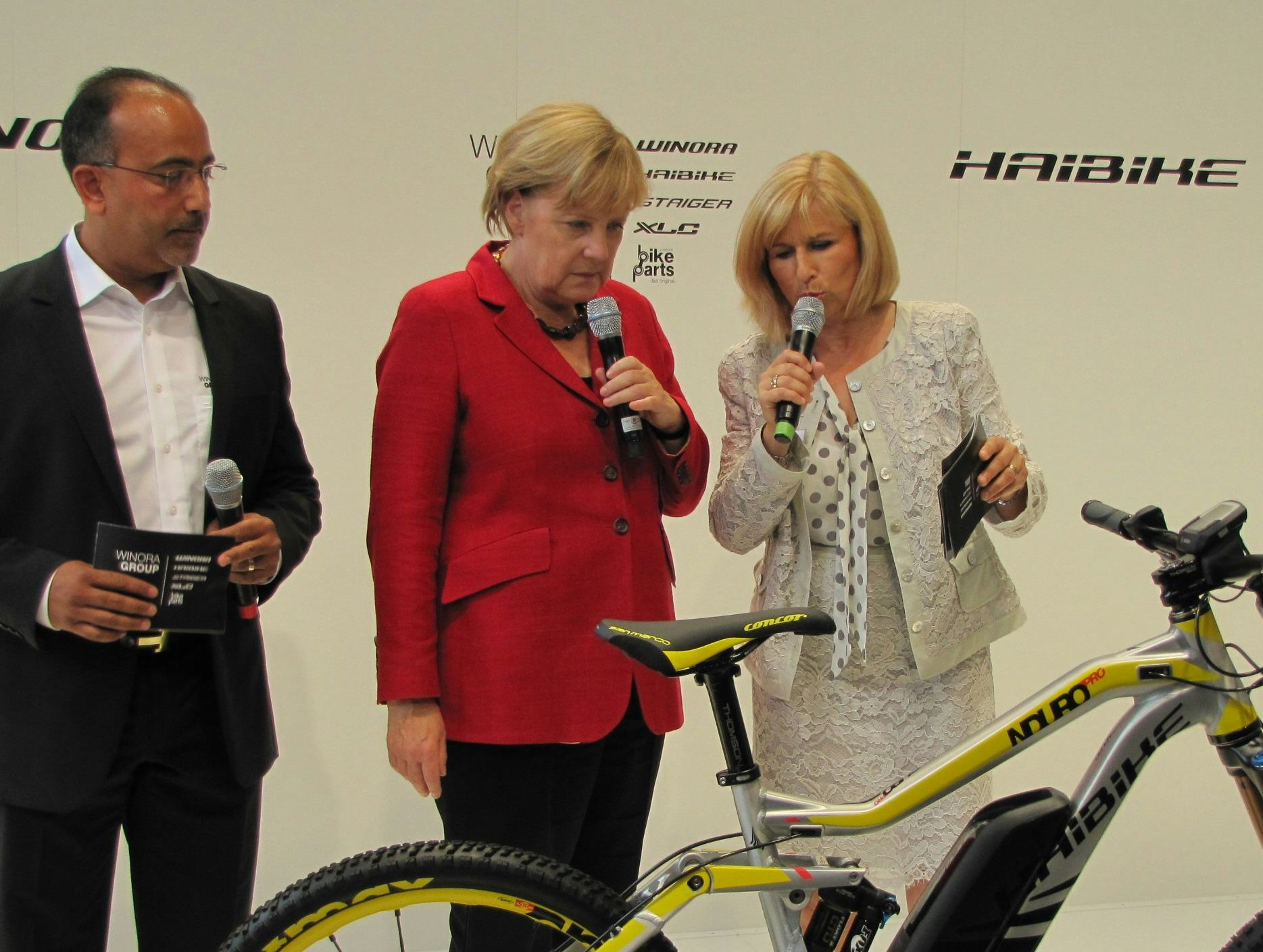Will Susanne (right) and Felix Puello (left), presenting the latest Haibikes to the German Chancellor Angela Merkel at Eurobike 2014. – Photo Bike Europe